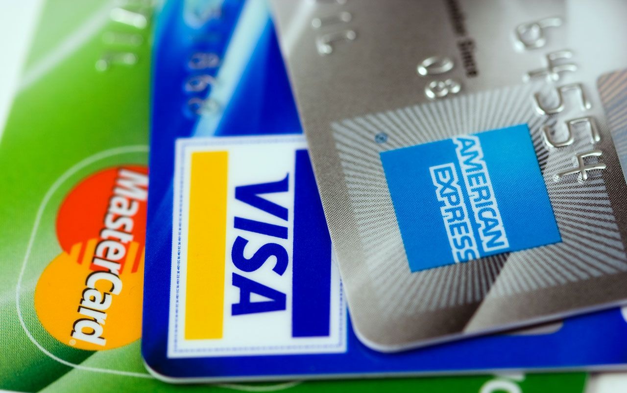 A close-up shot of 3 credit cards in green, blue, and silver.