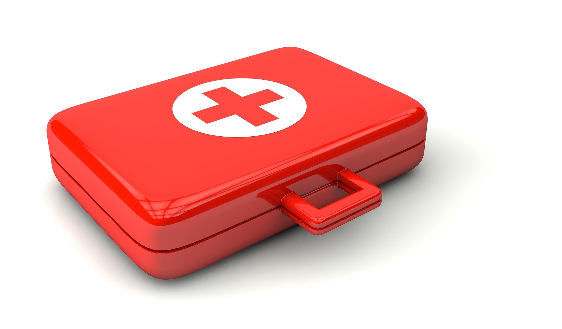 A red first aid kit with the red and white cross on the top, setting on a white background.