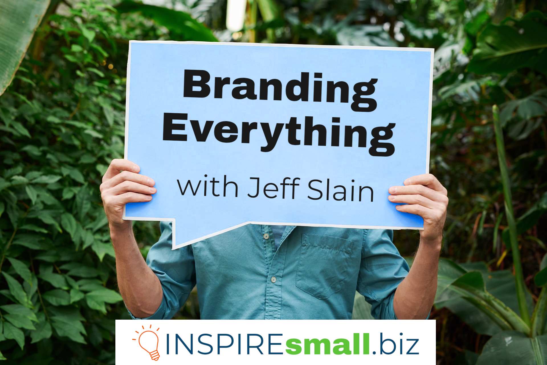 A person holding a sign in front of a background of green plants. The sign says Branding Everything with Jeff Slain, and a white card at the bottom that says INSPIREsmall.biz.
